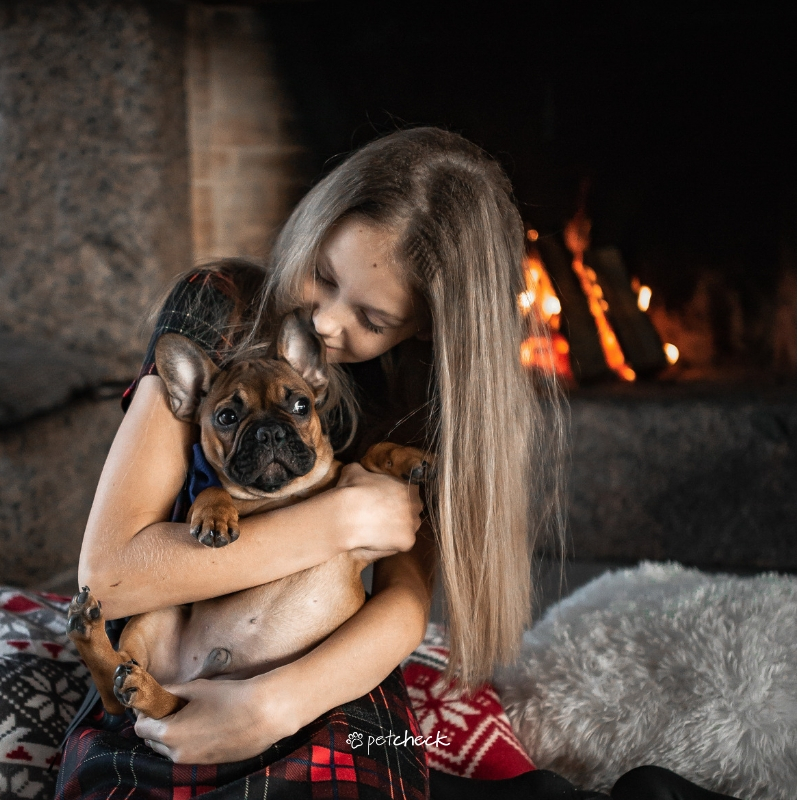 child hugging a French bulldog